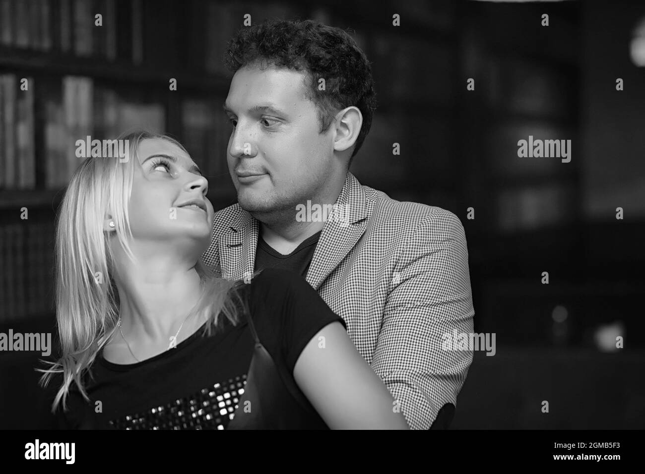 Jeune couple, une fille avec un jeune homme qui s'embrasse et pose sur l'appareil photo. Jeune famille. Le mari dans la veste encadre sa femme. Banque D'Images