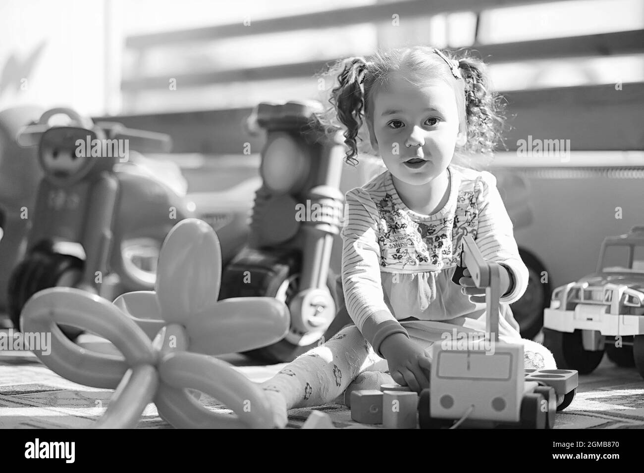 Enfant dans la chambre des enfants. L'enfant est assis sur le rebord de la fenêtre. Heureux l'enfant avec les jouets. Banque D'Images