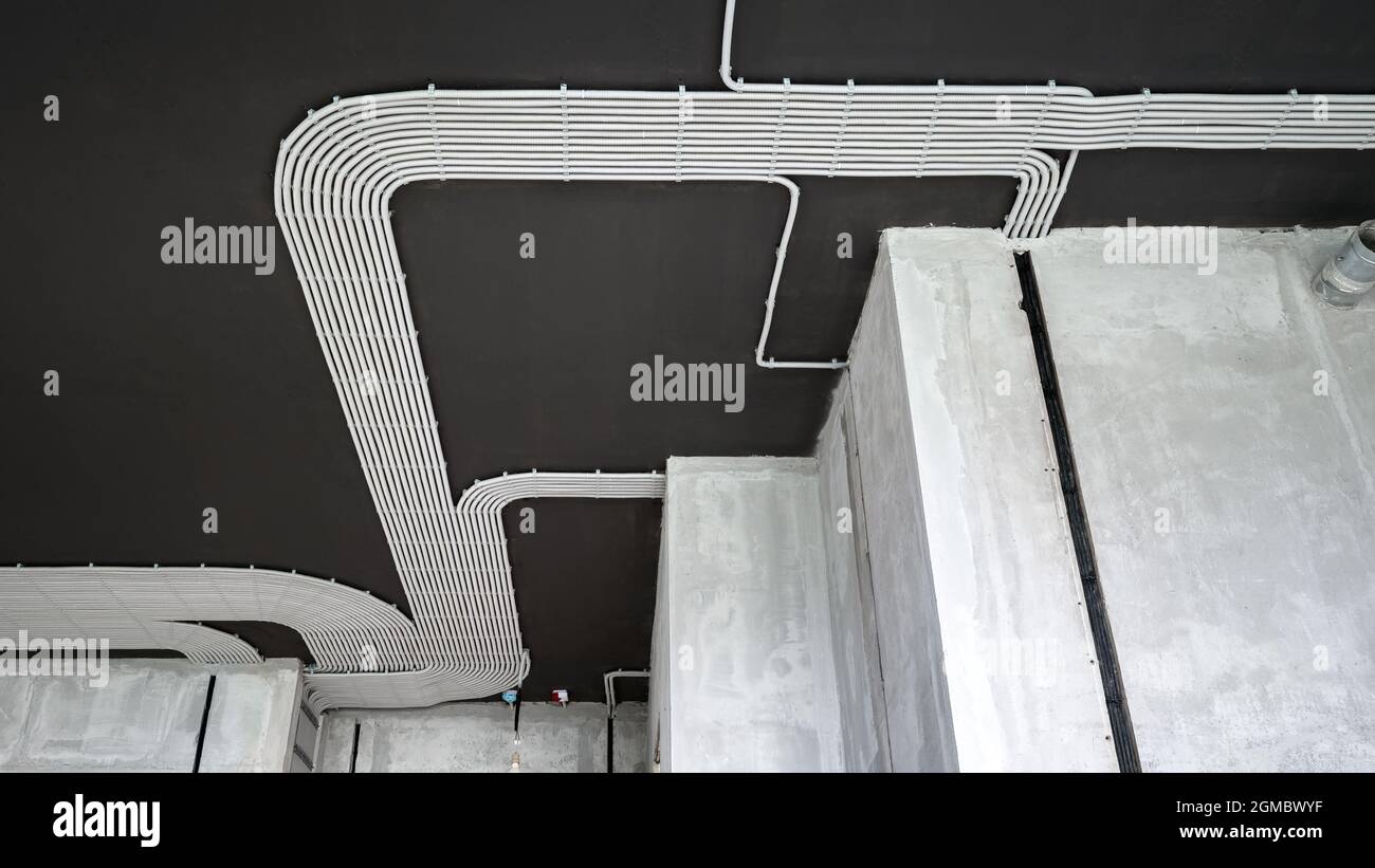 Câbles et tuyaux électriques sur le plafond en béton de la maison. Tuyaux et conduits modernes en plastique avec fils dans la pièce. Lignes de tubes de câblage en pvc après la professiono Banque D'Images