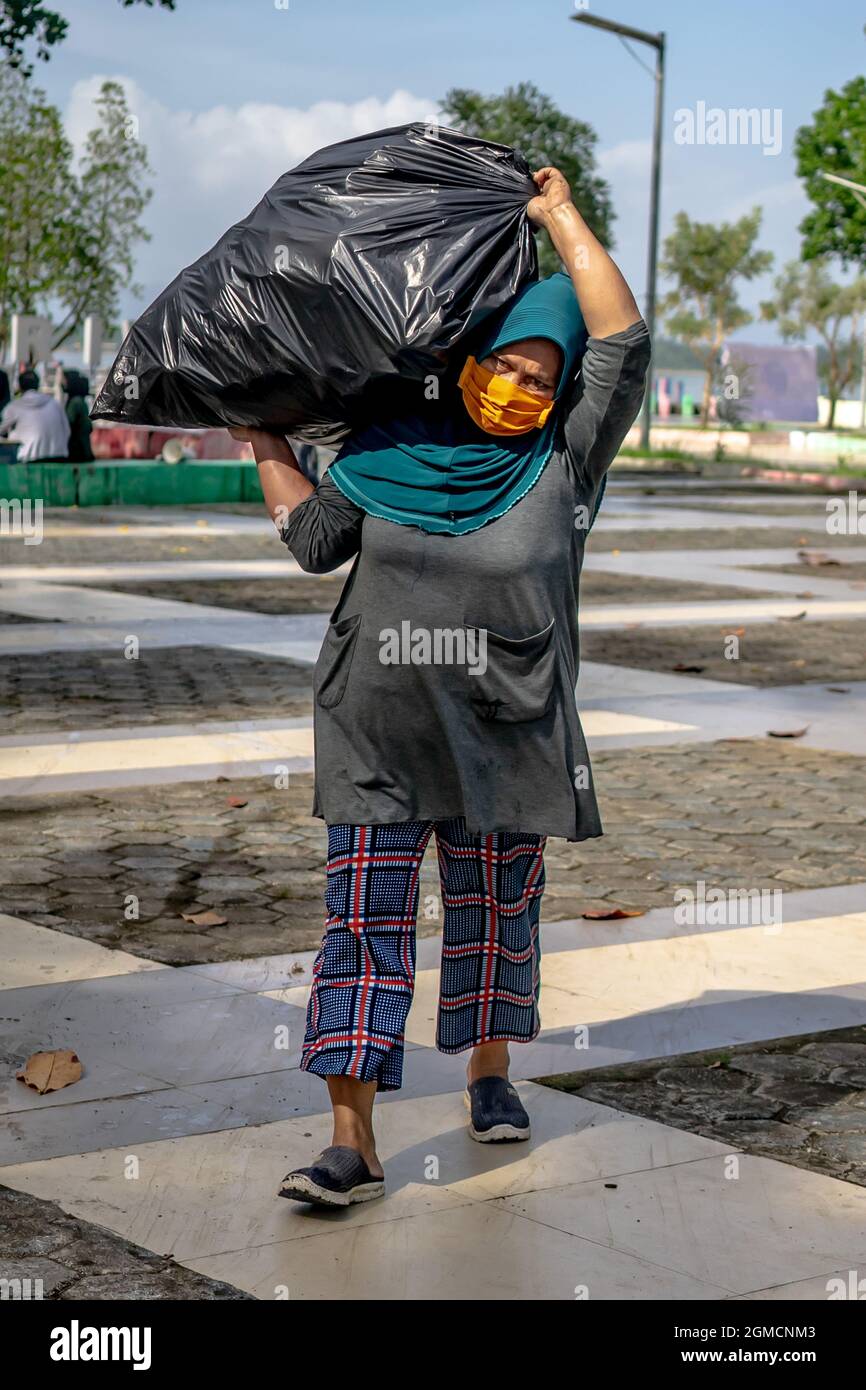 Kendari, Sulawesi du Sud-est, Indonésie. 18 septembre 2021. Une femme responsable des ordures transporte les ordures dans du plastique pour les mettre ensemble. La Journée mondiale de nettoyage aura lieu cette année à nouveau simultanément dans 180 pays, dont l'Indonésie en général et à une occasion spéciale le 18 septembre 2021. L'objectif de cette campagne pour nettoyer autant de détritus que possible! Et surtout, obtenir des informations plus précieuses sur le type de déchets dans les rues et dans l'environnement et son origine. Cette idée est indispensable pour trouver des solutions structurelles. (Credit image: © Andry Denisah/ZUMA Press Wire) Credit: ZU Banque D'Images