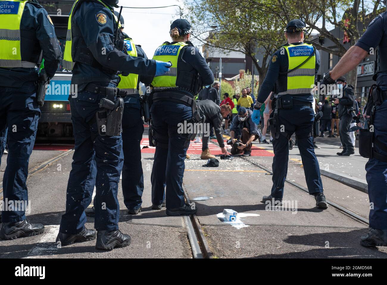 Melbourne, Australie. 18 septembre 2021. Une bouteille de lait est cassée sur le sol après avoir été jetée à la police tandis qu'un manifestant ramasse un chapeau de police assis dans de la mousse de poivre. Credit: Jay Kogler/Alay Live News Banque D'Images