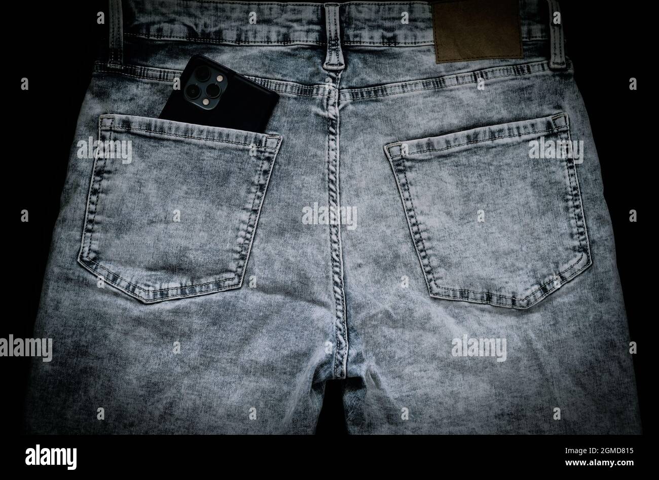 jeans en denim vieilli avec smartphone dans la poche arrière, dans le noir Banque D'Images