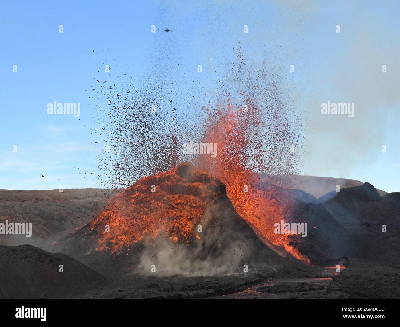Évent volcanique à Fagradalsfjall, Islande, éruption d'orange incandescent et de lave rouge. Lave noire au premier plan et ciel bleu en arrière-plan. Banque D'Images