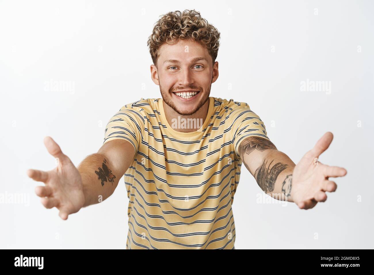 Beau homme blond tendre les mains pour tenir quelqu'un, en étirant les bras pour le câlin, en attendant la grande cuddle, debout sur fond blanc Banque D'Images