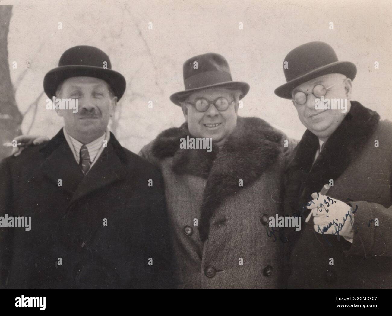 photographie vintage originale de 1933. Trois amis sont debout pour ce tournage. Ils ressemblent à des personnes très riches, posh, riches. Porter des manteaux tendance et fumer la cigarette et le cigare. Banque D'Images