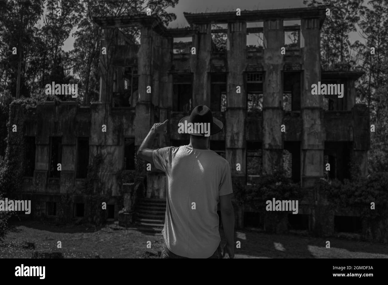 Vue arrière de l'homme en chapeau de cow-boy pointant vers l'horreur maison abandonnée. Banque D'Images