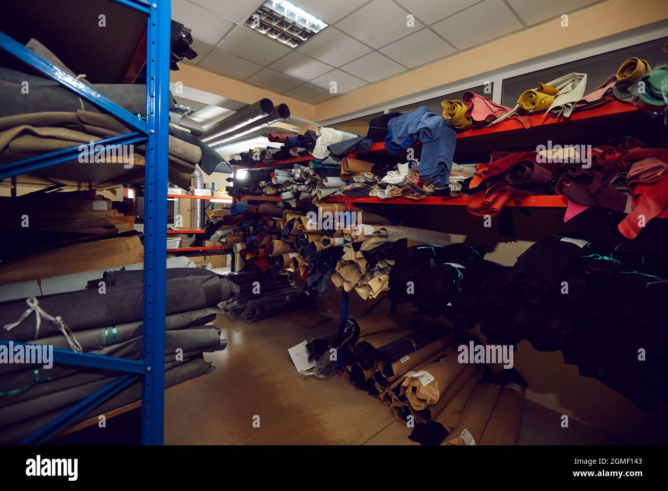 Rangées de tablettes de rangement pleines de rouleaux en tissu et en cuir à l'usine de chaussures ou de vêtements Banque D'Images