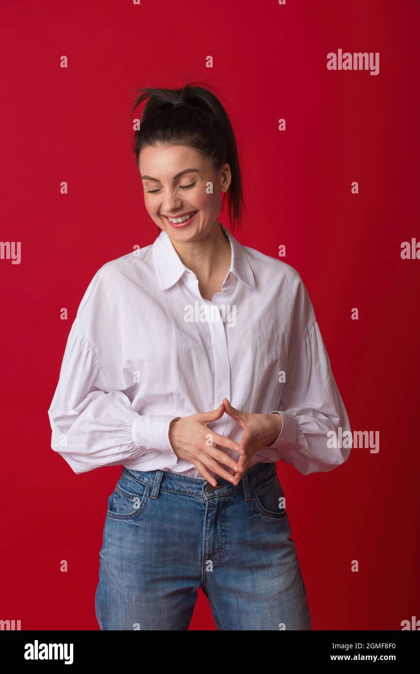 Bonne jeune femme souriante. Femme des années 30 vêtue d'une chemise  blanche décontractée et d'un Jean bleu classique en studio et regardant  loin de l'appareil photo Photo Stock - Alamy