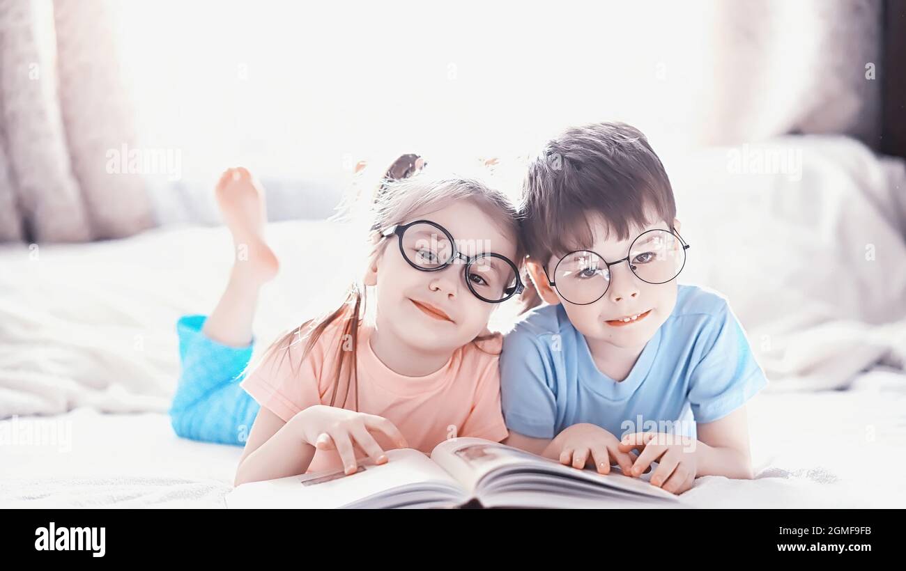 Les enfants s'étendent sur le lit à côté du nouveau-né, petite sœur. Émotions des enfants. Banque D'Images