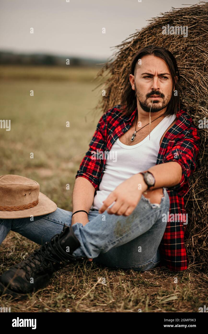 Jeune homme serbe beau dans une chemise en flanelle et un Jean déchiré  adossé sur une botte de foin Photo Stock - Alamy