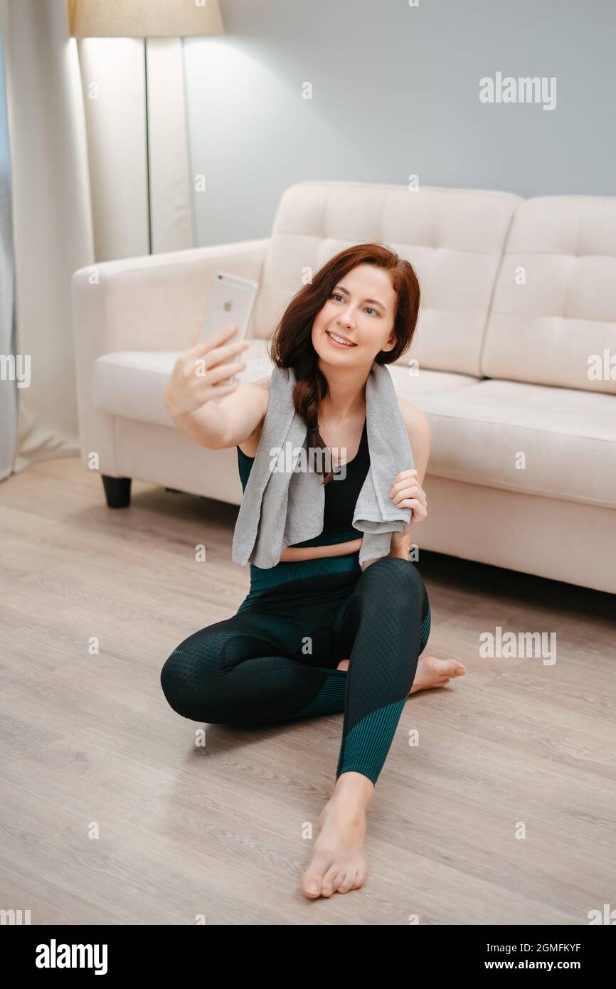 Femme après des exercices de yoga avec une serviette prend des photos d'elle-même au téléphone. Banque D'Images