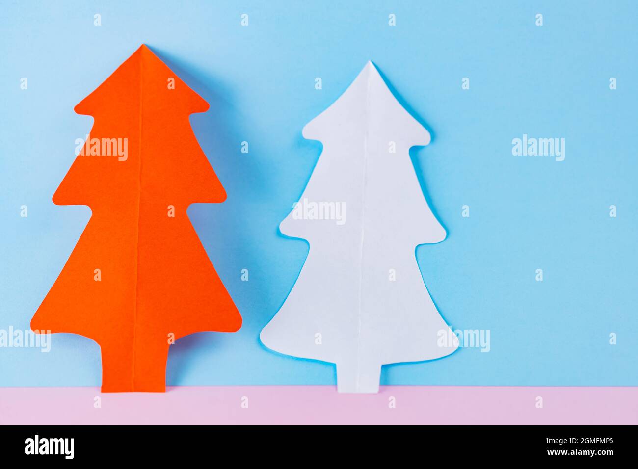 Arbres de Noël en papier sur fond bleu-rose. Arbres de noël en papier blanc et rouge. Noël concept minimal Banque D'Images