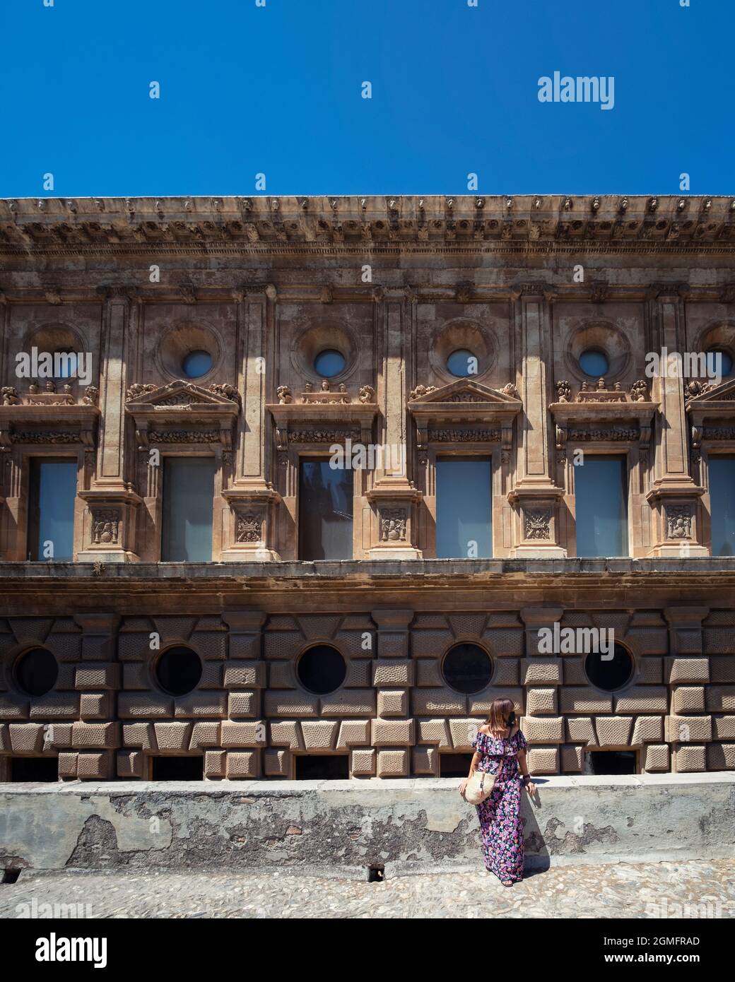 Femme caucasienne avec une longue robe d'été posant devant le Palais de Charles V. Banque D'Images