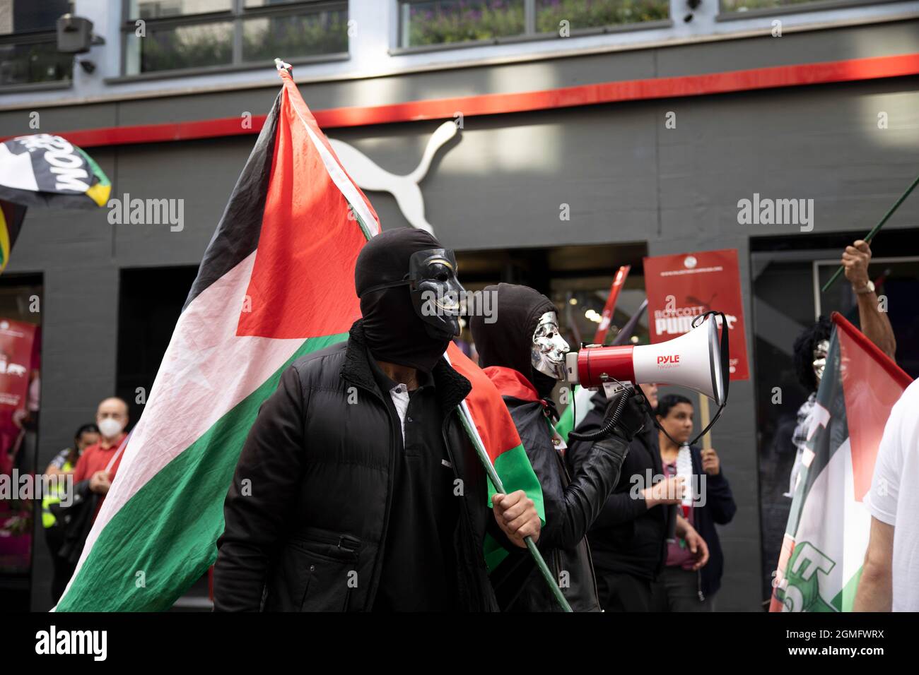 Londres, Royaume-Uni. 18 septembre 2021. Des partisans palestiniens masqués tenant des drapeaux palestiniens à l'extérieur du magasin phare de Puma à Carnaby Street pendant la manifestation.Une campagne de boycott mondial a été lancée par des partisans palestiniens contre Puma en révision de leur parrainage de l'Association israélienne de football. Un petit groupe de contre-manifestants soutenant Israël s'est présenté lors de l'action de boycott à l'extérieur du magasin phare de Puma à Londres. Crédit : SOPA Images Limited/Alamy Live News Banque D'Images