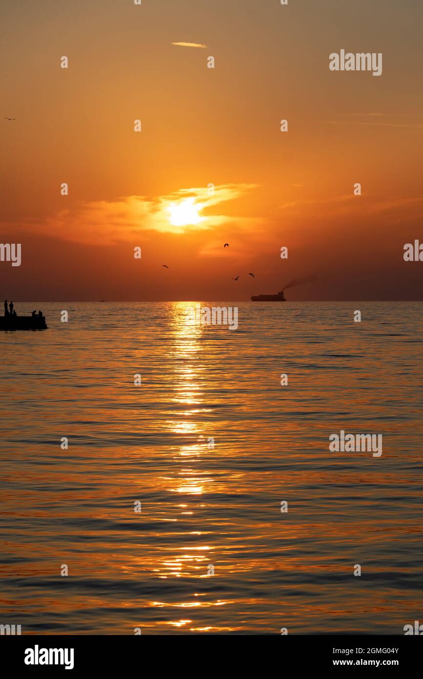 coucher de soleil à trieste avec silhouette d'oiseaux poissons et de gens sur la jetée . Banque D'Images