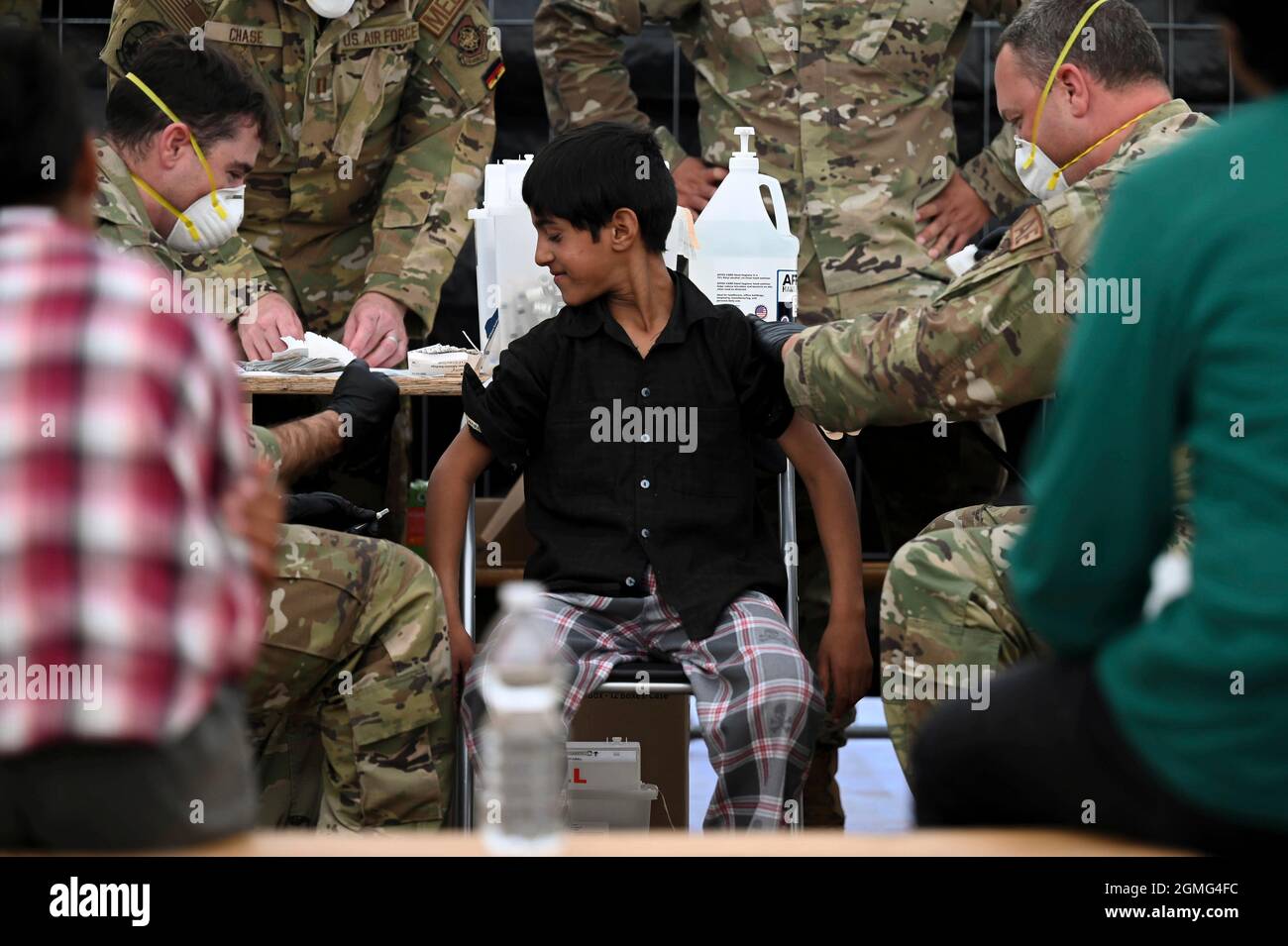 Ramstein-Miesenbach, Allemagne. 18 septembre 2021. Un aviateur de la US Air Force administre des vaccins contre les oreillons, la rougeole et la rubéole et contre la varicelle à un enfant afghan évacué de Kaboul à la base aérienne de Ramstein le 17 septembre 2021 à Ramstein-Miesenbach, en Allemagne. Ramstein fournit un hébergement temporaire aux personnes évacuées d'Afghanistan dans le cadre de l'opération alliés refuge. Crédit : TSgt. Devin Nothstine/États-Unis Air Force/Alamy Live News Banque D'Images