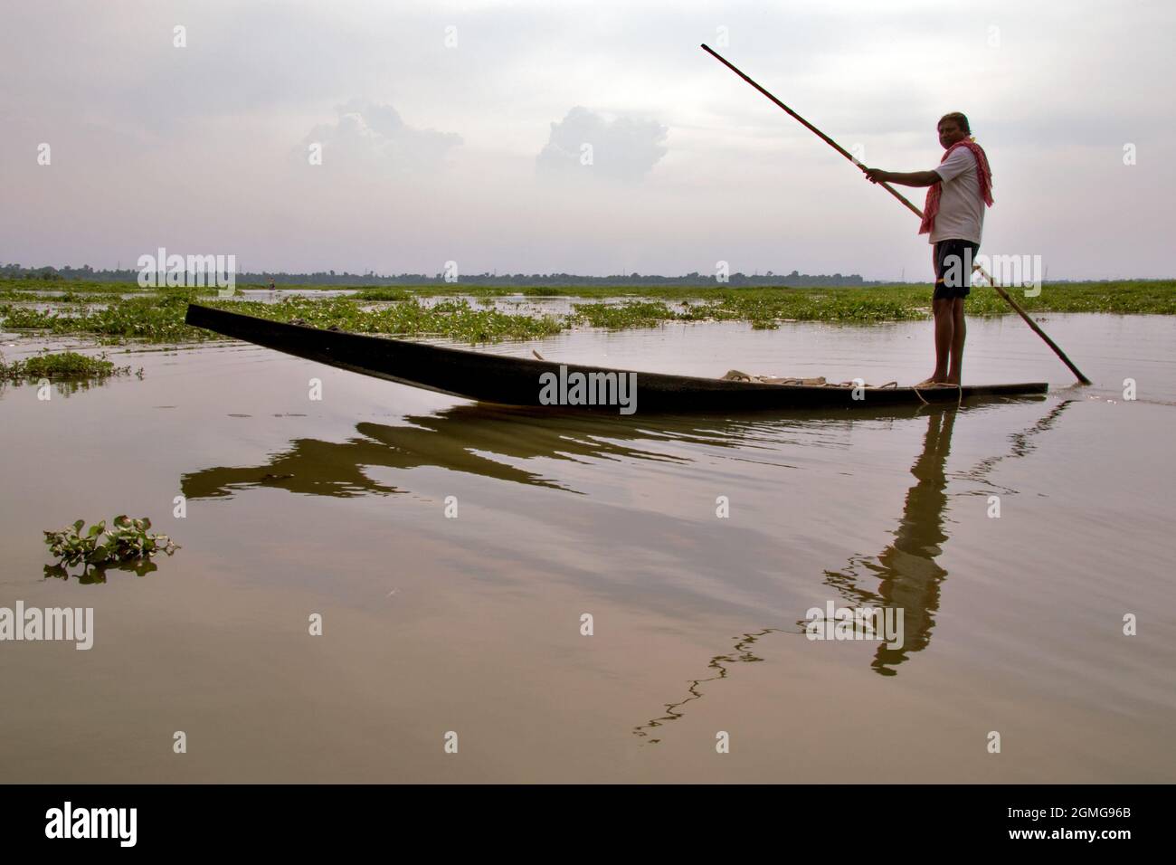 Photo du coucher de soleil dans le village rural Bengal où un boatman est vu conduire son bateau. Banque D'Images
