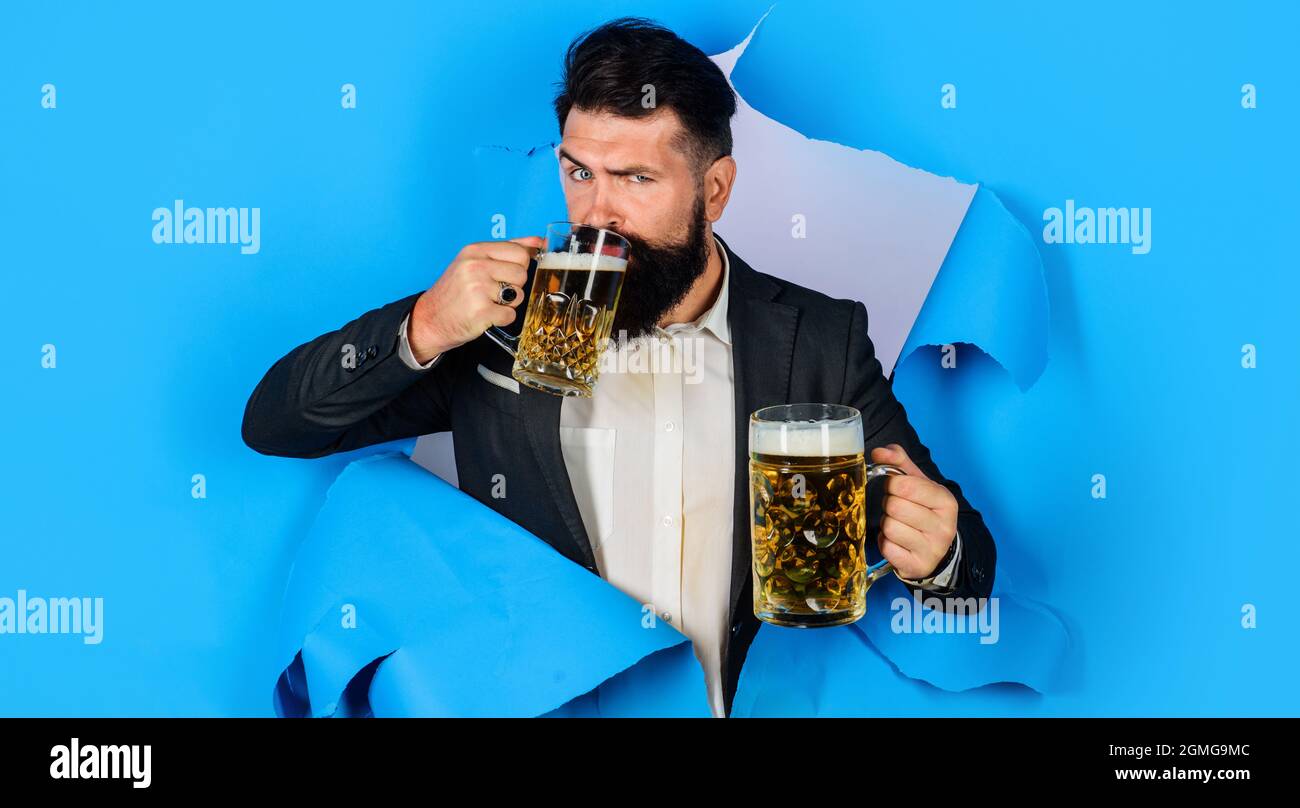 Homme barbu avec deux tasses de bière regardant à travers trou de papier. Bière élégante pour hommes. Lager et sombre. Oktoberfest. Banque D'Images