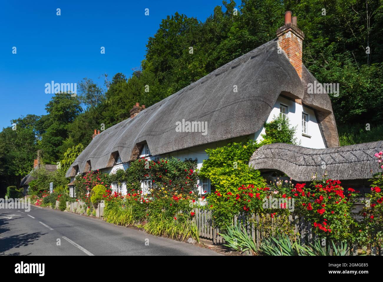Angleterre, Hampshire, Test Valley, Wherwell, maison de campagne traditionnelle de chaume et route vide Banque D'Images