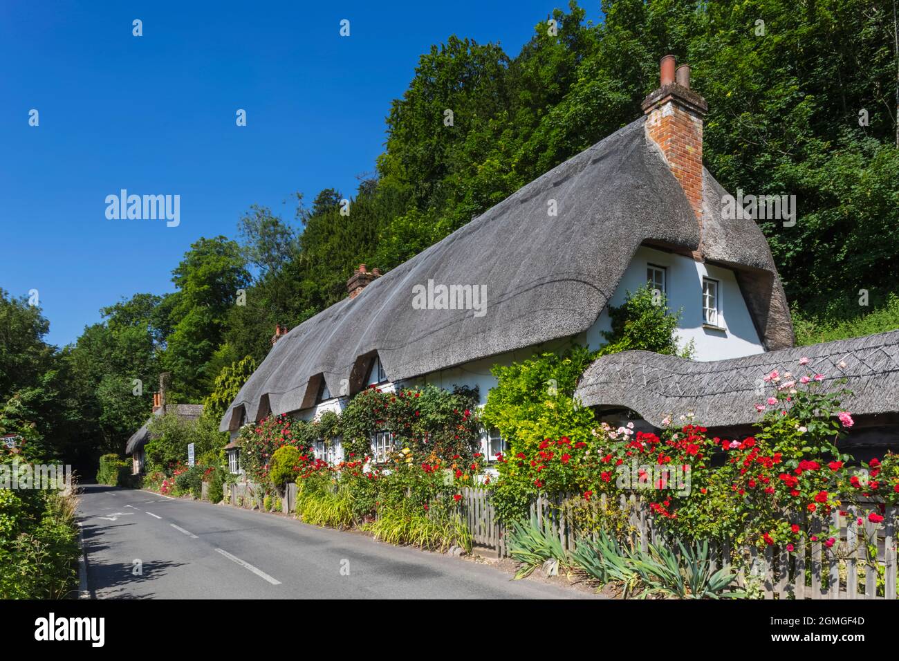 Angleterre, Hampshire, Test Valley, Wherwell, maison de campagne traditionnelle de chaume et route vide Banque D'Images