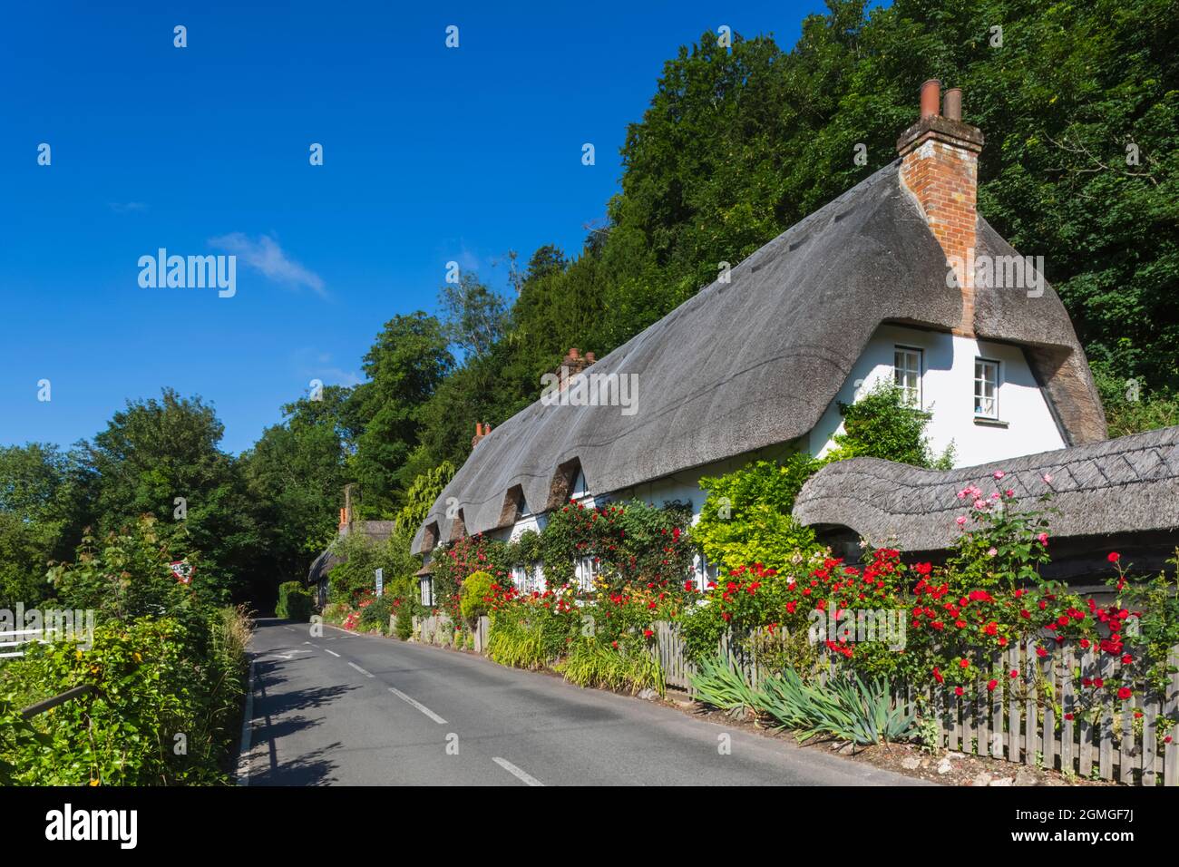 Angleterre, Hampshire, Test Valley, Wherwell, maison de campagne traditionnelle de chaume et route vide Banque D'Images
