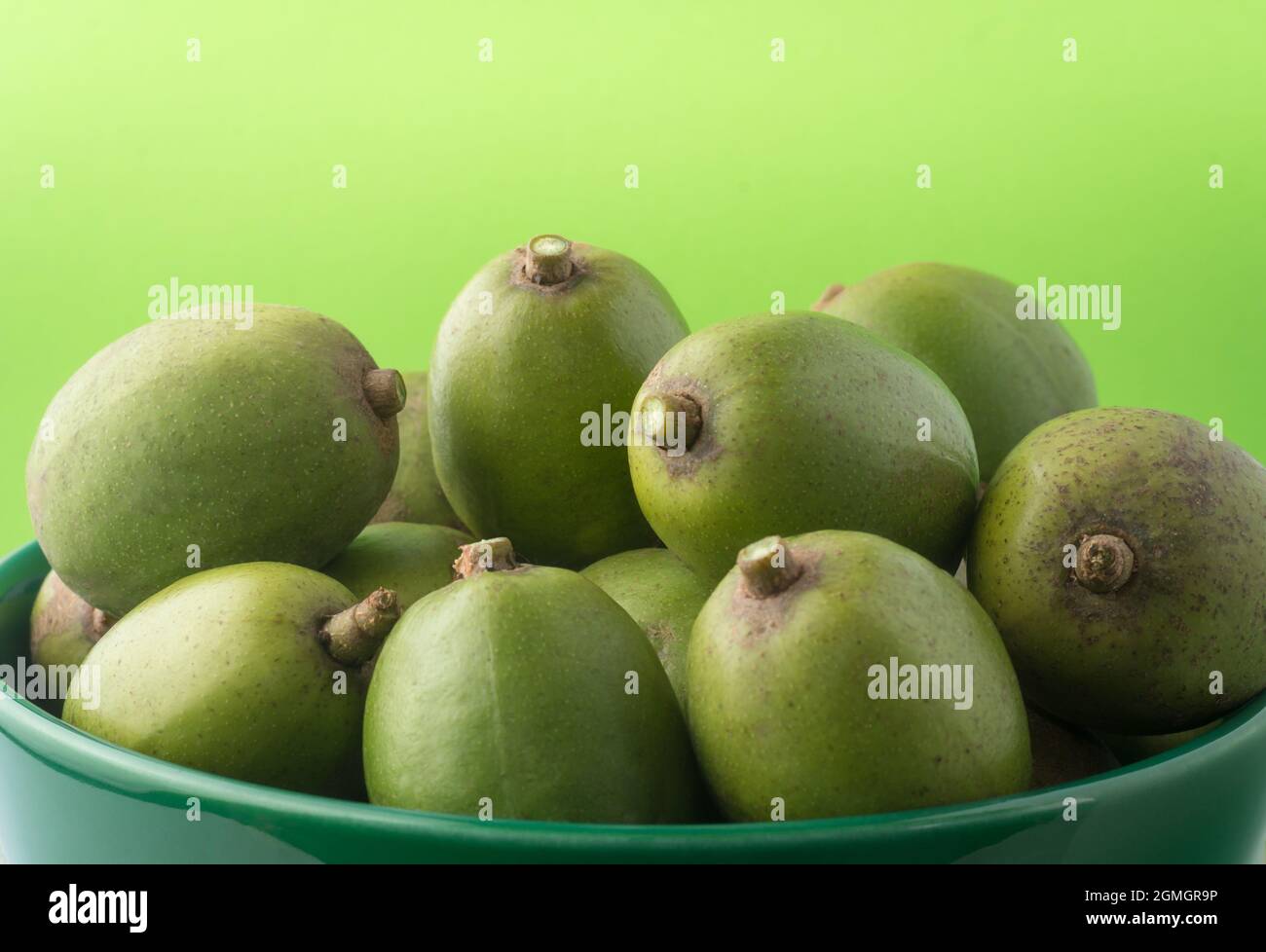 ambarella ou curry de prune de juin, fruits comestibles dans un bol, vue rapprochée prise sur un fond vert clair Banque D'Images