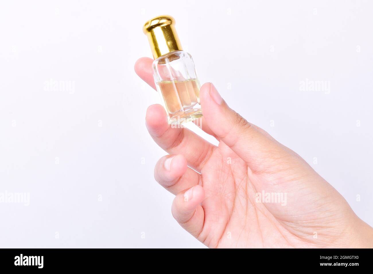 bouteille d'huile essentielle à la main isolée sur fond blanc, huile aromatique ou bouteille de parfum attar dans la main de la femme sur fond blanc Banque D'Images