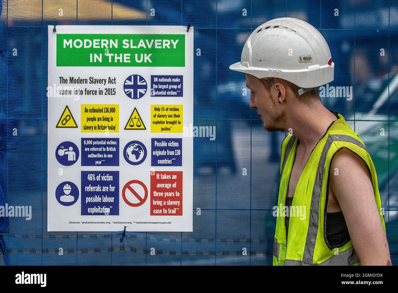 L'esclavage moderne, le travail forcé des panneaux de type EPI sur le site de construction d'escrime, Justice en mouvement, Lancashire rencontre des performances antiesclavagistes parkour acrobates portant des vestes haute visibilité ou des gilets divertissent les foules sur le marché Preston Flag, au Royaume-Uni Banque D'Images