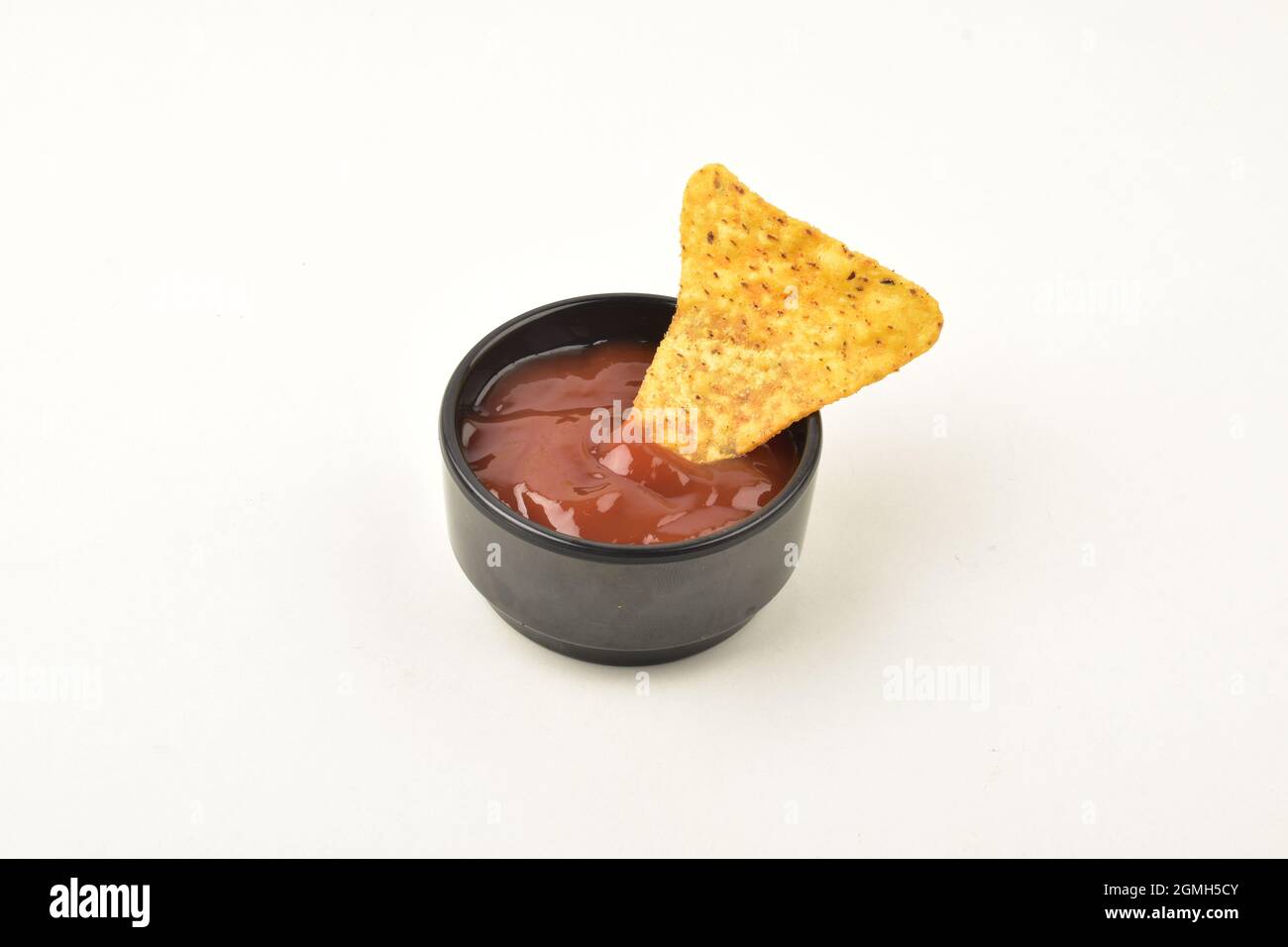 Une seule pastille de nacho trempée dans une sauce sur fond blanc Banque D'Images
