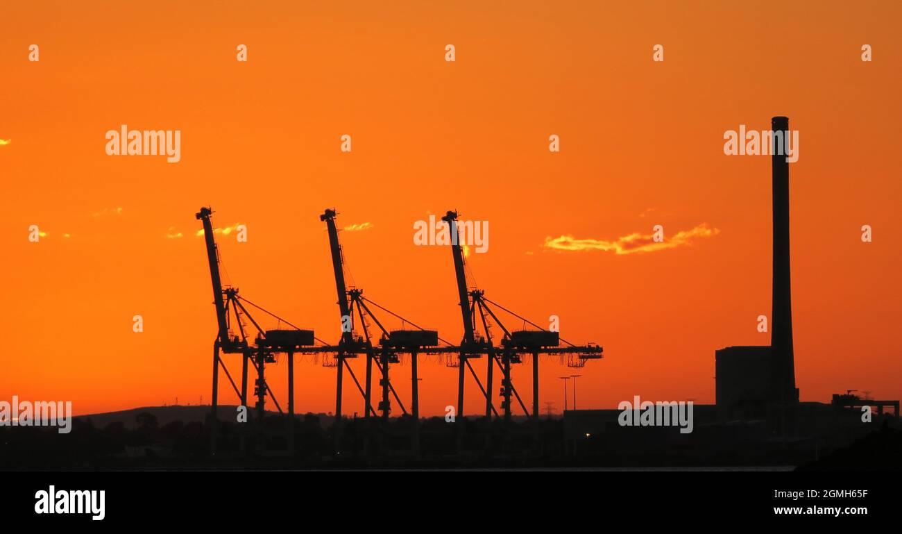 Silhouette au coucher du soleil. Grues silhouetées au port de Melbourne alors que le soleil se couche. Banque D'Images