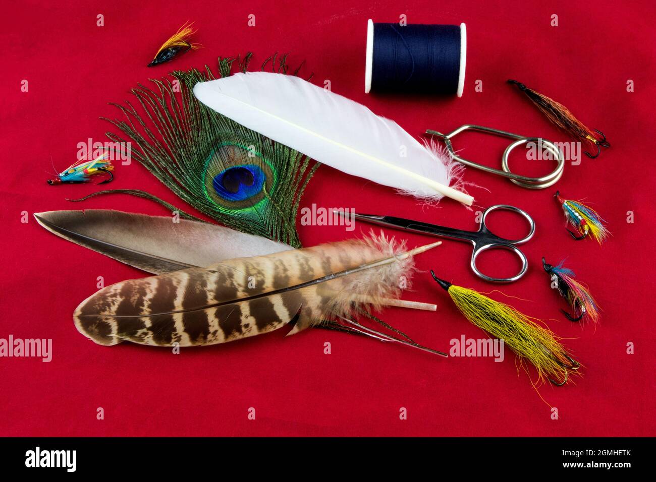Mouche de pêche nouant des outils et des plumes sur un chiffon de table rouge marbré Banque D'Images