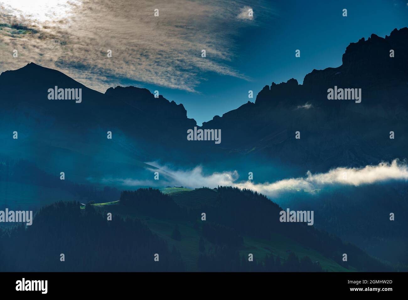Beim Sonnenaufgang beleuchtete Alp mit einer Nebelbank in Adelboden, im hintergrund Bonderspitze und Grosser Lohner, Berner Oberland, Schweiz Banque D'Images