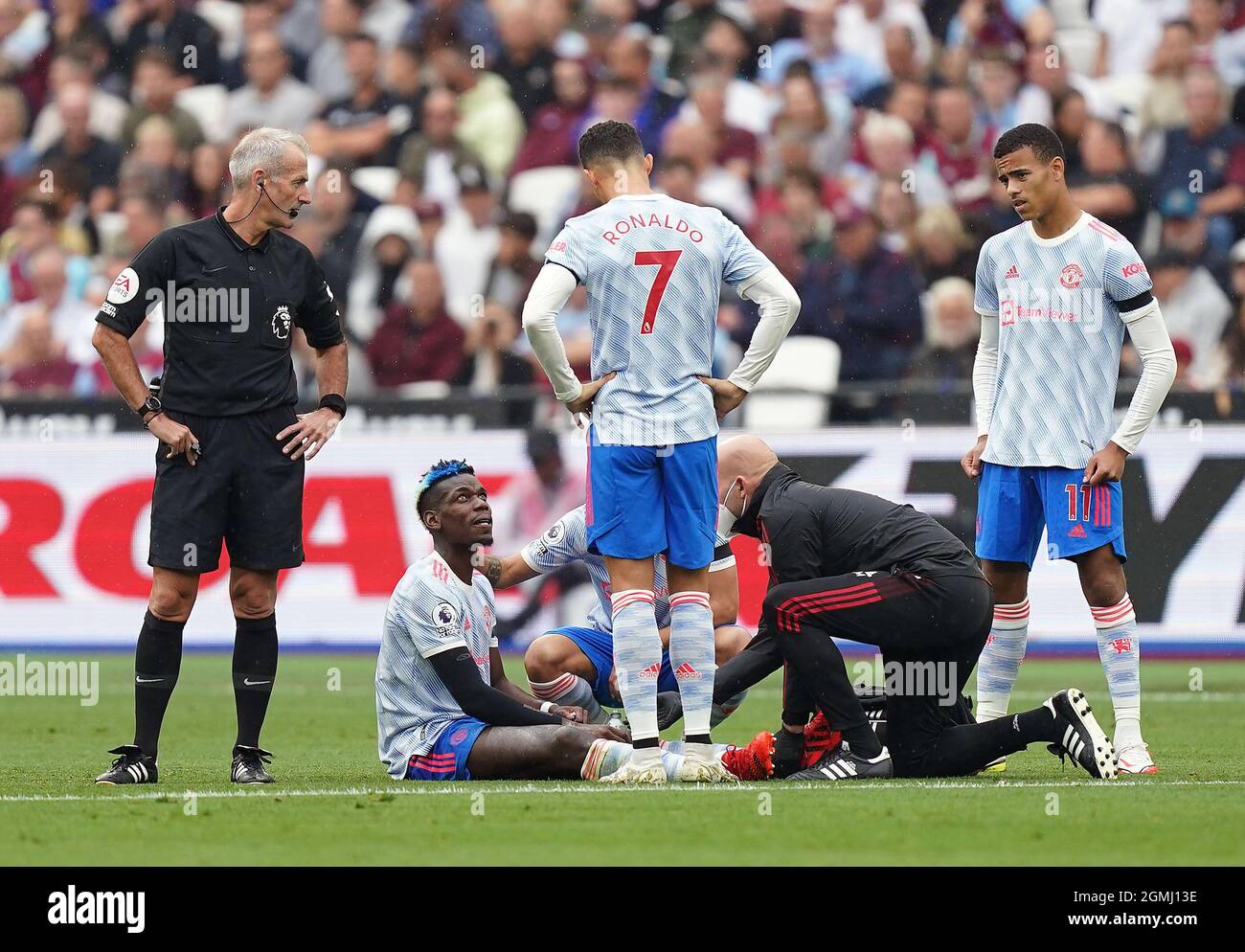 L'arbitre Martin Atkinson (à gauche), Cristiano Ronaldo de Manchester United et Mason Greenwood regardent alors que Paul Pogba reçoit un traitement pour une blessure lors du match de la Premier League au London Stadium, Londres. Date de la photo: Dimanche 19 septembre 2021. Banque D'Images