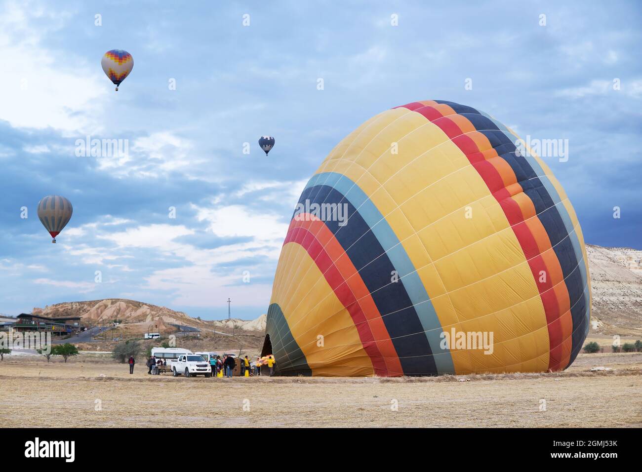 Touristes attendant l'équipage pour chauffer le ballon d'air à un point de lancement en Cappadoce, Turquie Banque D'Images