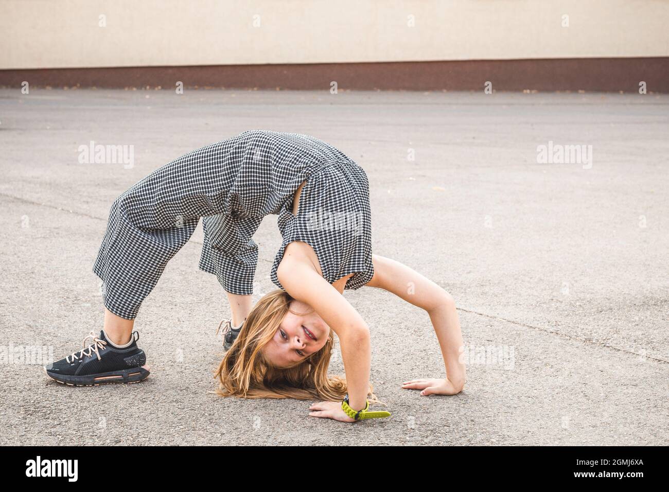 Petite fille blonde souriant et faisant la pose de pont Banque D'Images