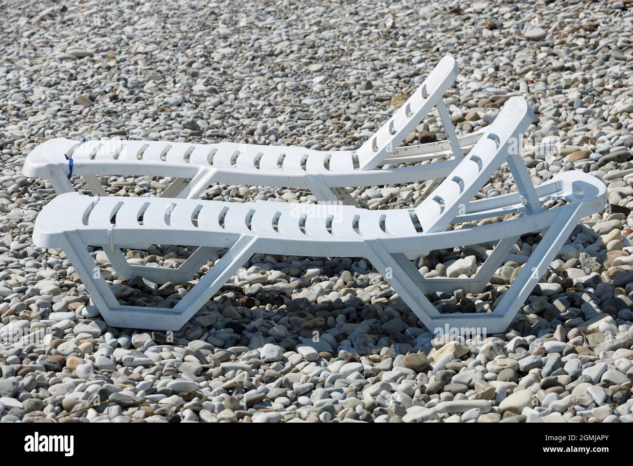 deux chaises longues blanches sur la plage de galets en été. Photo de haute qualité Banque D'Images