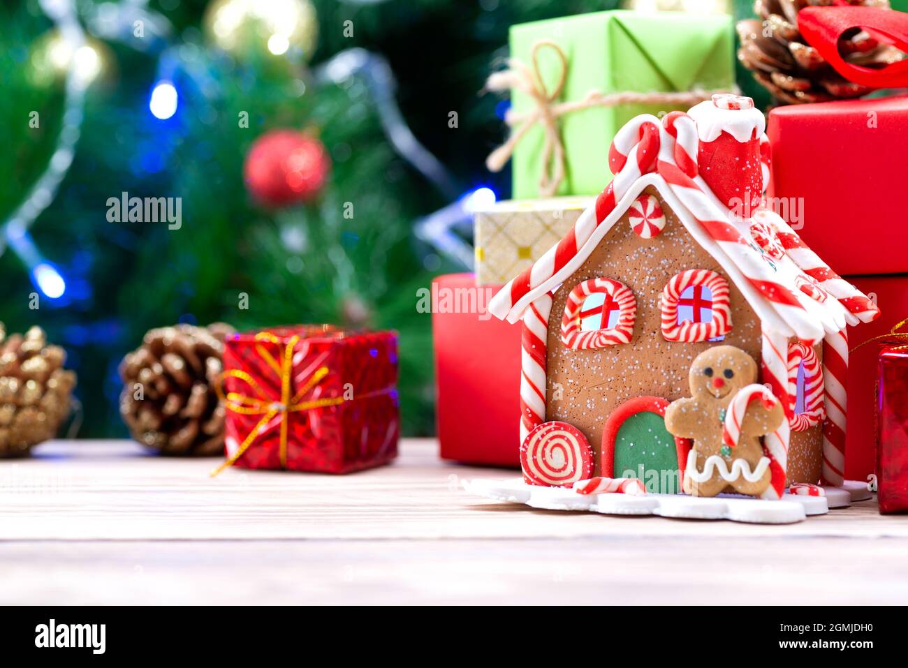 Maison de Noël faite de biscuits de pain d'épice décorée dans un esprit de Noël avec un arbre de Noël en arrière-plan. Maison de pain d'épice sur le Banque D'Images