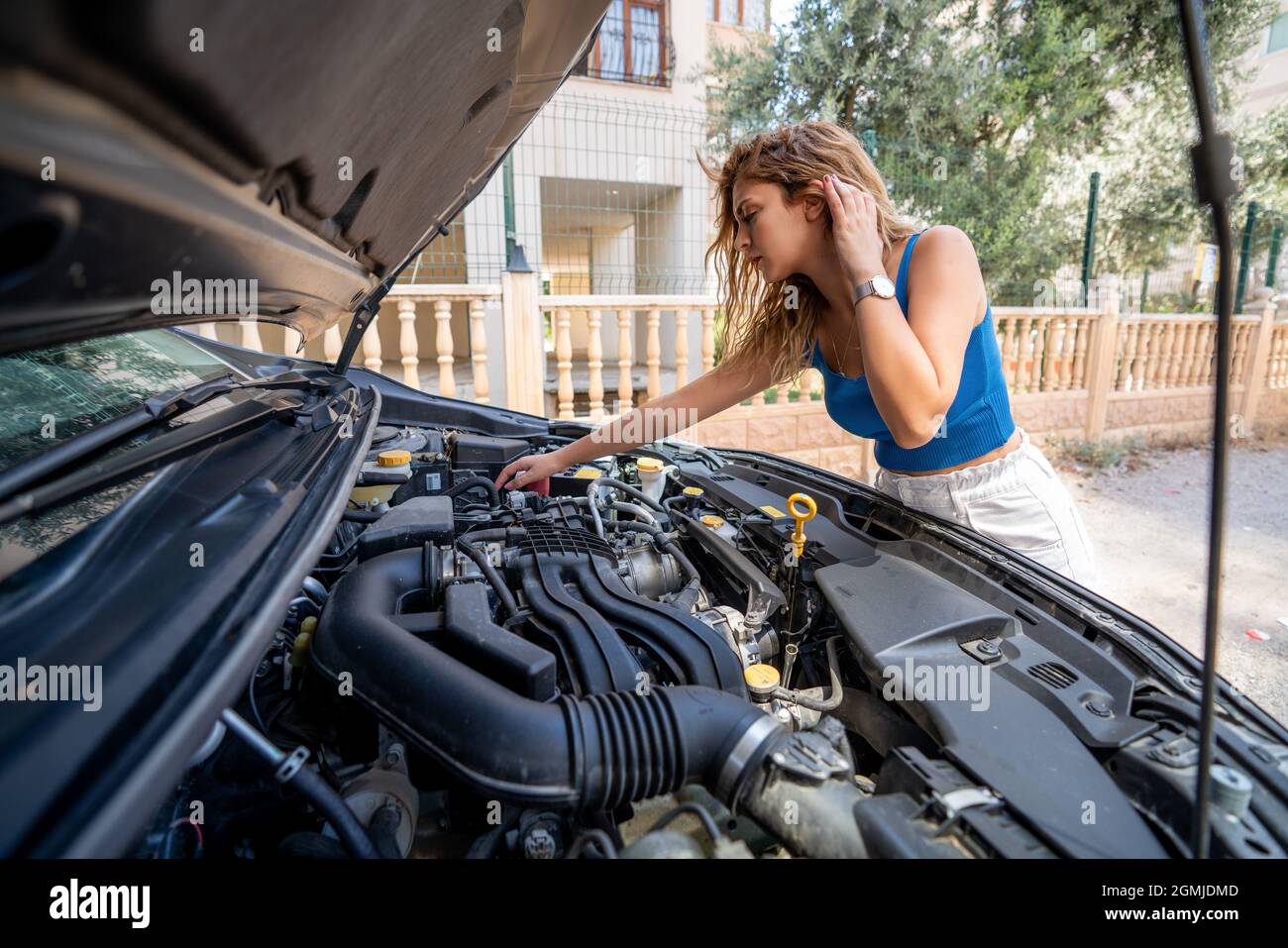 La jeune femme cherche à ouvrir le capot de la voiture pour le dépannage. Concept de transport et de véhicule. Photo de haute qualité Banque D'Images
