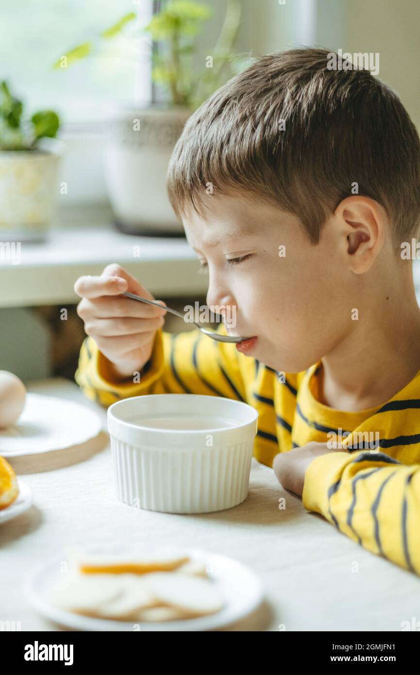 Le Petit Dejeuner Est Servi Le Matin Avec Des Cereales Et Du Lait Petit Dejeuner Dans La Cuisine Avant L Ecole Le Garcon Mange A La Table Pres De La Fenetre Photo Stock