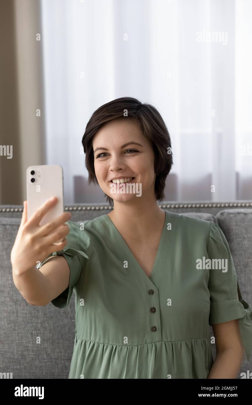 Belle femme s'attendant à un bébé assis sur un canapé prendre un joli selfie Banque D'Images