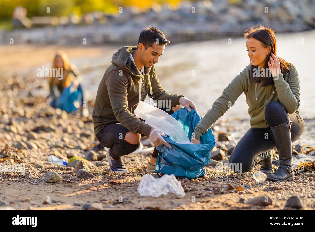 Une équipe de bénévoles dévoués et souriants collectant les ordures en plastique à la plage Banque D'Images