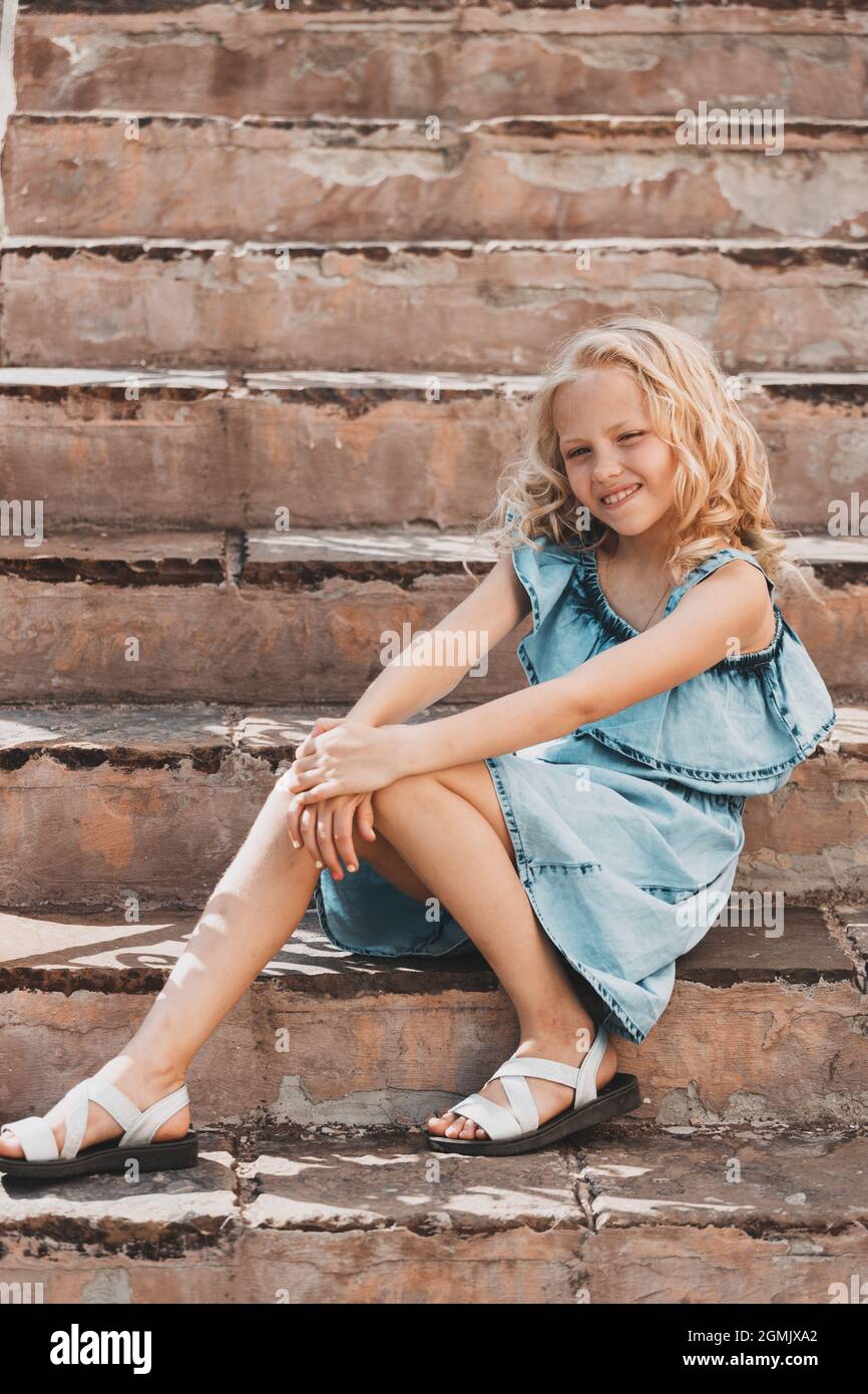une jeune fille blonde dans une robe bleue pose sur les marches de l'escalier.  Photo de haute qualité Photo Stock - Alamy