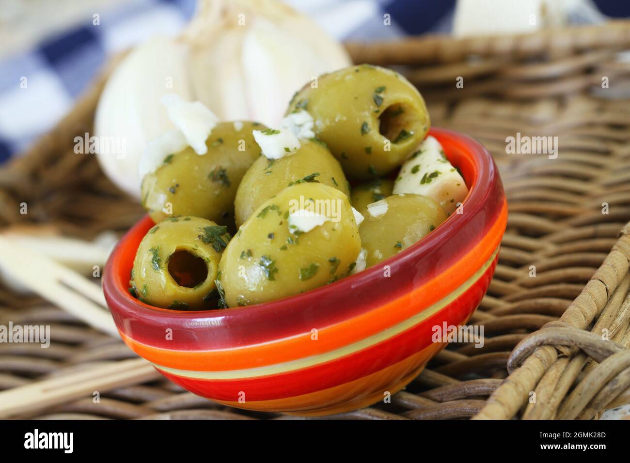 Olives vertes mûres et délicieuses avec ail frais dans un bol en argile coloré, en gros plan Banque D'Images