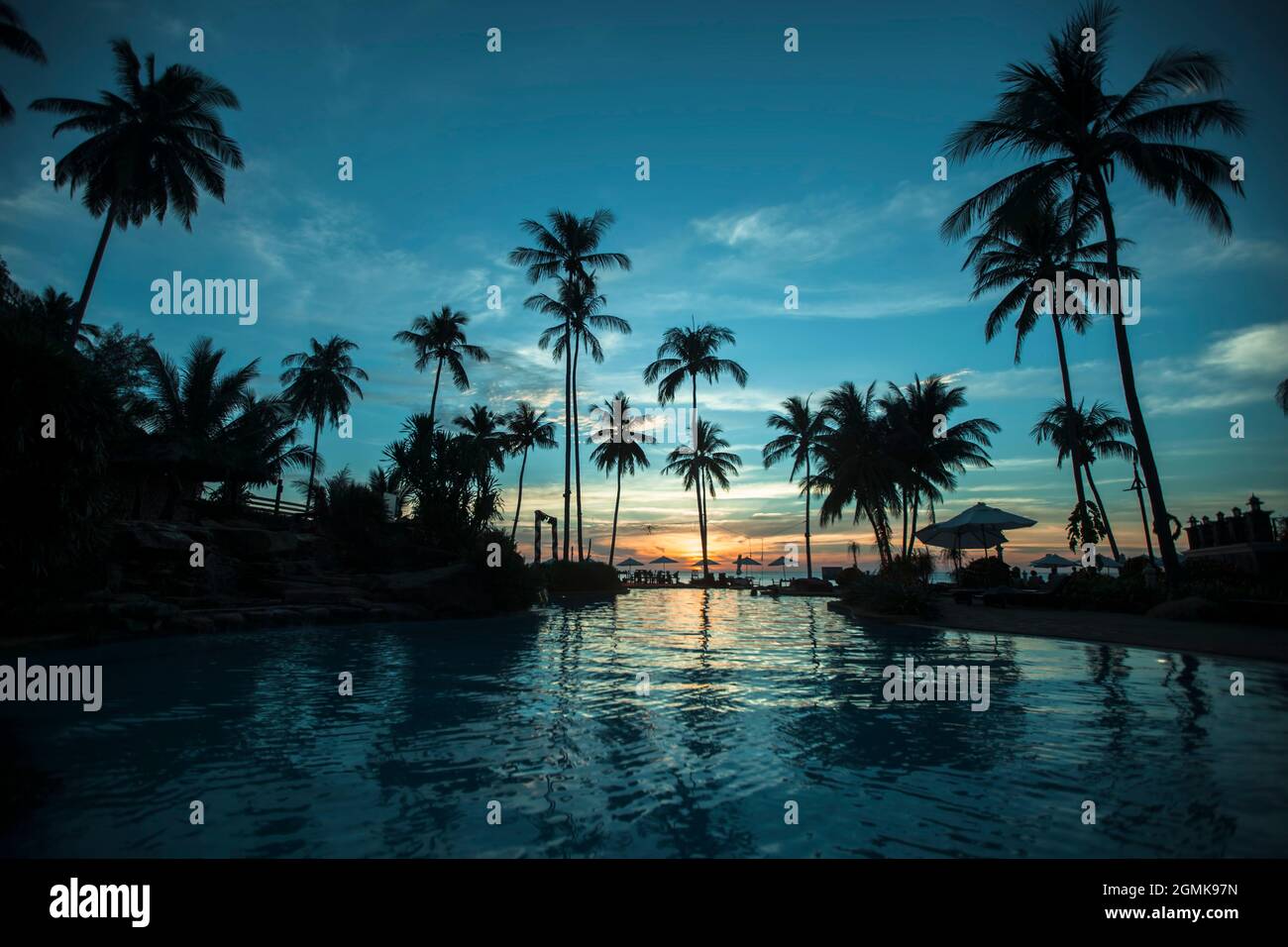 Silhouettes des palmiers à la plage tropicale pendant le coucher du soleil paradisiaque. Banque D'Images
