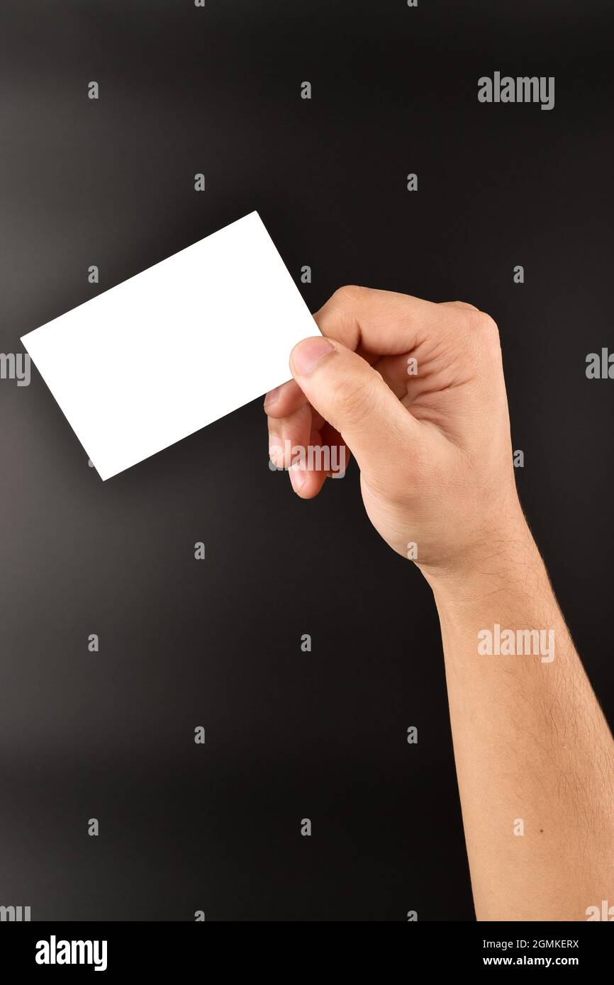 main tenant une carte de visite vierge sur fond sombre, carte blanche pour message et texte publicitaire Banque D'Images