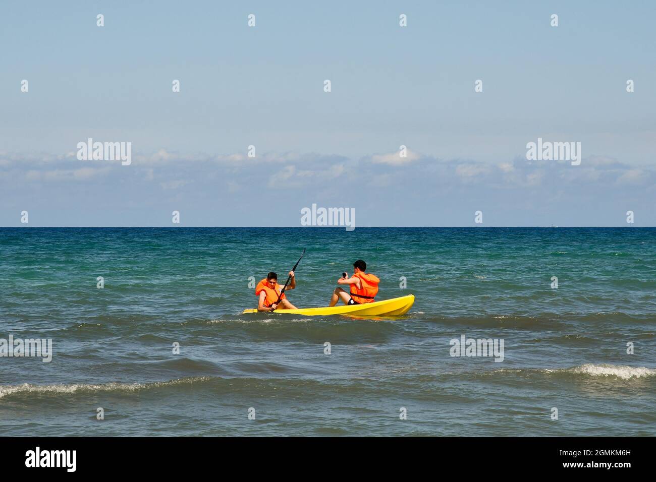 Deux gars avec des gilets de sauvetage canoë sur la mer dans une journée ensoleillée d'été avec ciel bleu clair, San Vincenzo, Livourne, Toscane, Italie Banque D'Images
