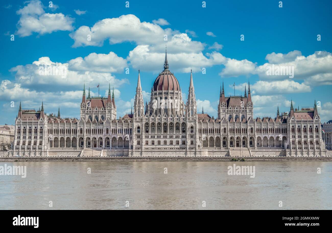 Vue d'été du Parlement hongrois construit dans le style néo-gothique le long du Danube avec une parfaite symétrie avec ciel bleu nuageux Banque D'Images