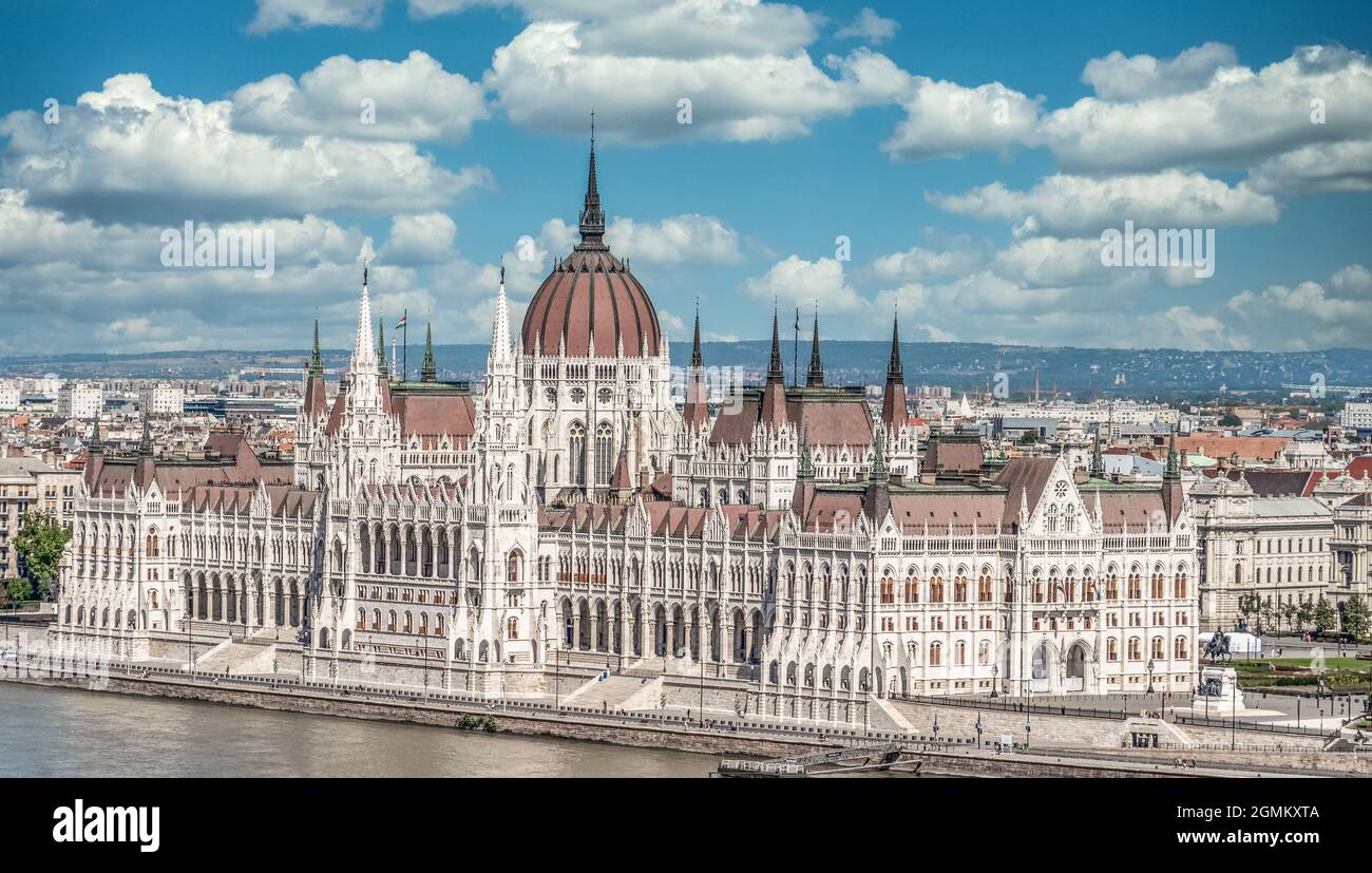 Vue d'été du Parlement hongrois construit dans le style néo-gothique le long du Danube avec une parfaite symétrie avec ciel bleu nuageux Banque D'Images
