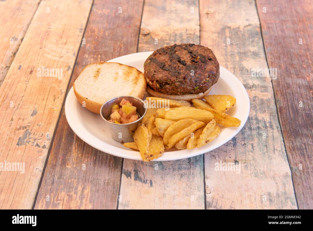 hamburger au bœuf grillé au charbon de bois avec pico de gallo et copeaux de bois sur table en bois Banque D'Images