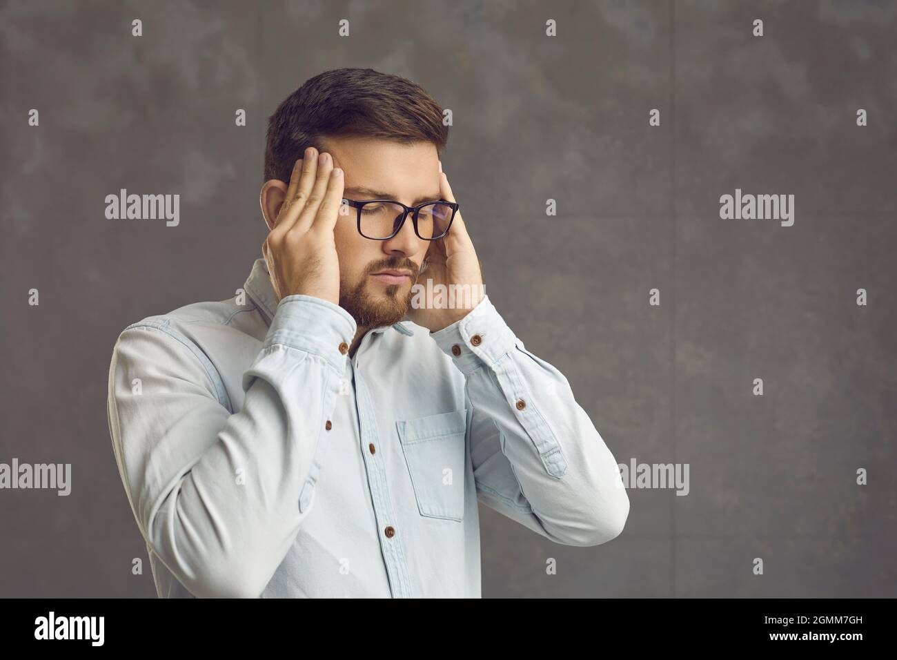 Smart sérieux jeune homme faisant un massage de la tête essayant de se calmer et de soulager le stress Banque D'Images